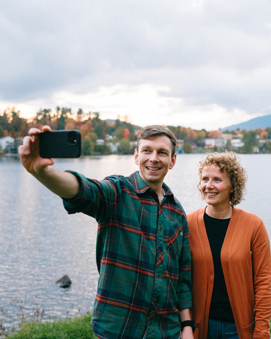 Two people taking a selfie by a lake with a scenic background